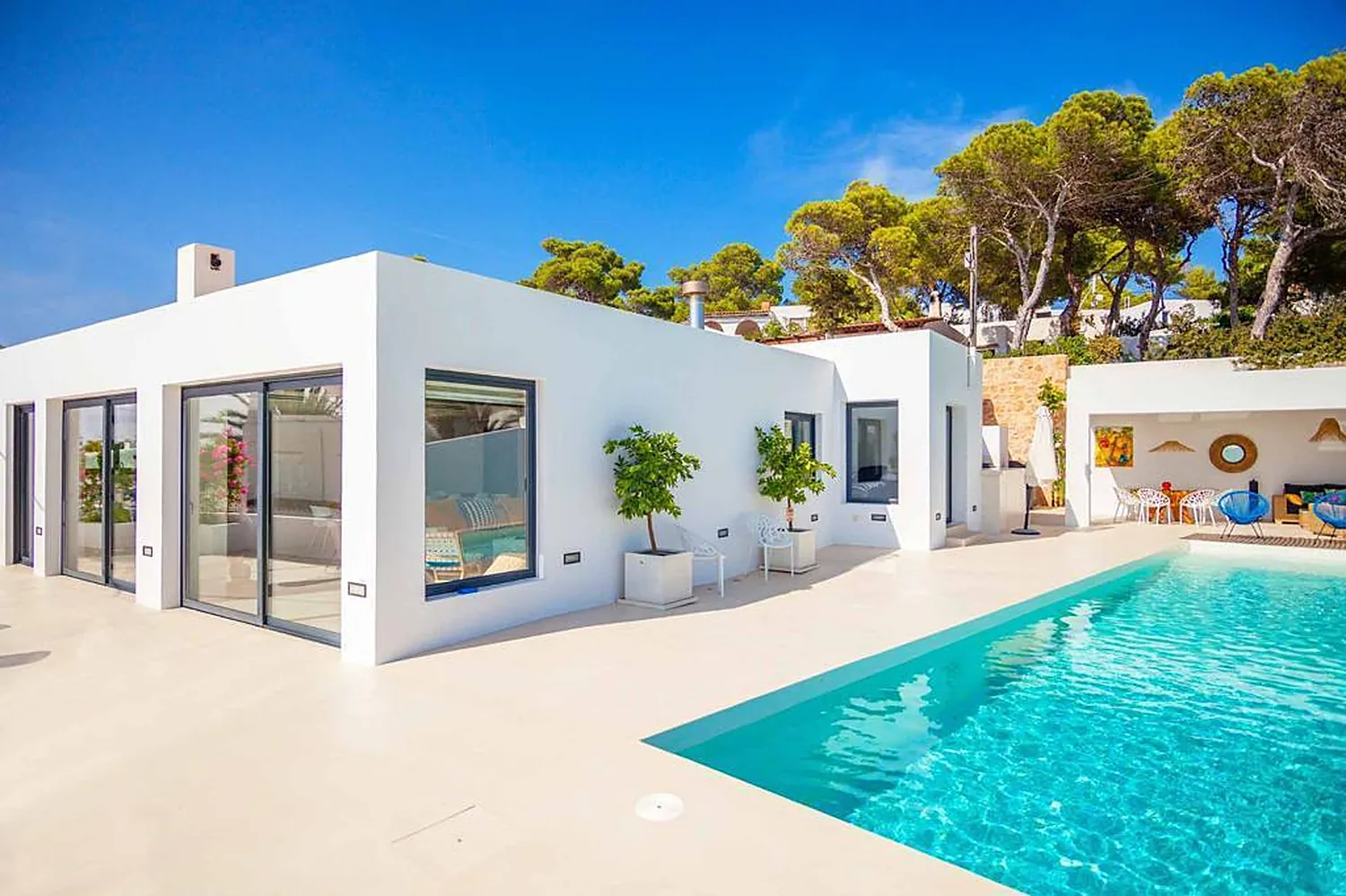 La villa blanca del retiro, de líneas contemporáneas, con piscina y pinos, en Ibiza.